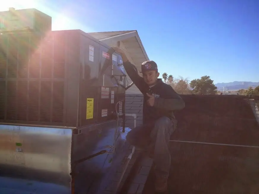 HVAC technician performing AC Tune-Up on a rooftop unit in Enterprise